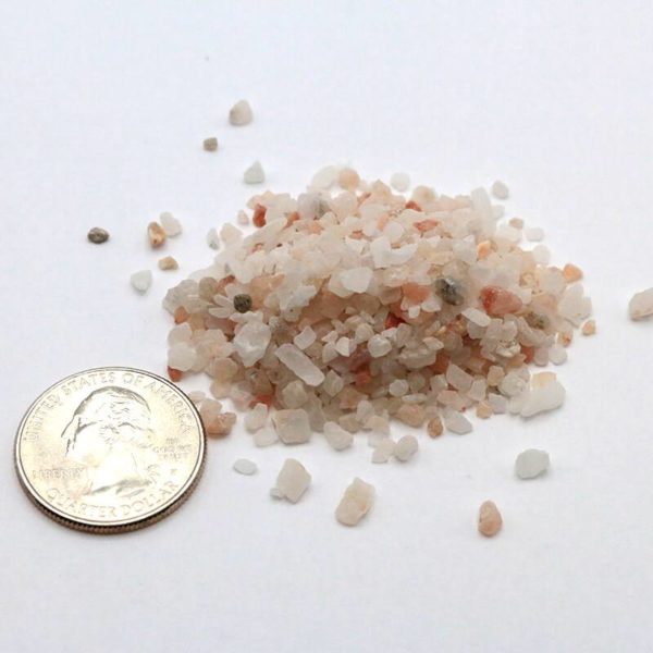 Small pile of langbeinite beside a quarter to show size; individual pieces are approximately 1/20th of a quarter